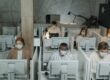 People working in a cubicle area while wearing masks,