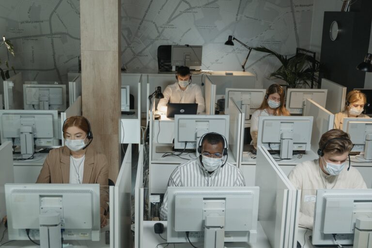COVID-19 Office Layout People working in a cubicle area while wearing masks,