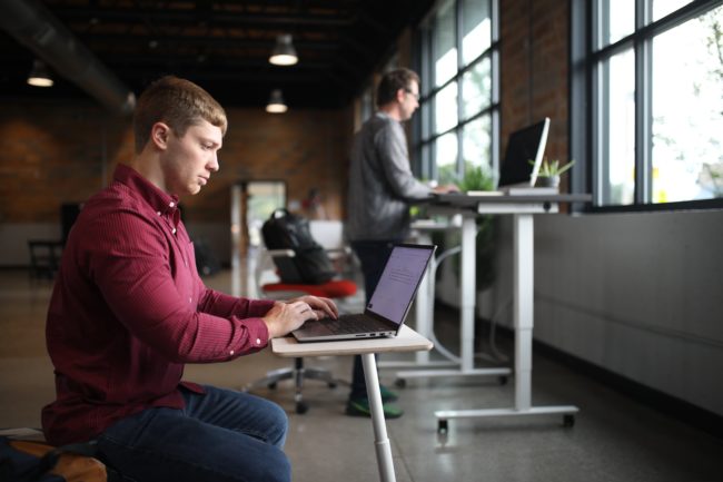 The Standing Desk Man sitting at a desk. Photo by TheStandingDesk on Unsplash